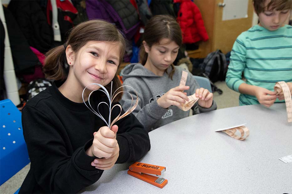 A girl holds a heart at the craft table